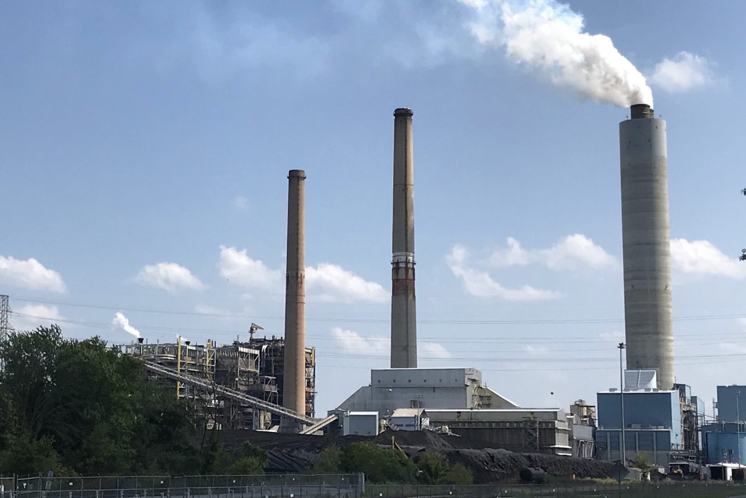 Smoke stakes at an industrial facility in front of a blue sky