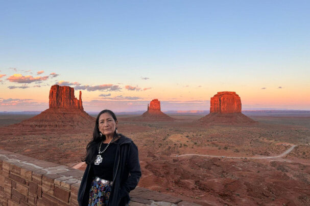 Former U.S. Secretary of the Interior Deb Haaland in a black jacket in front of red rock formations and a blue sky.