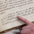 A finger pointing to a word in an old book