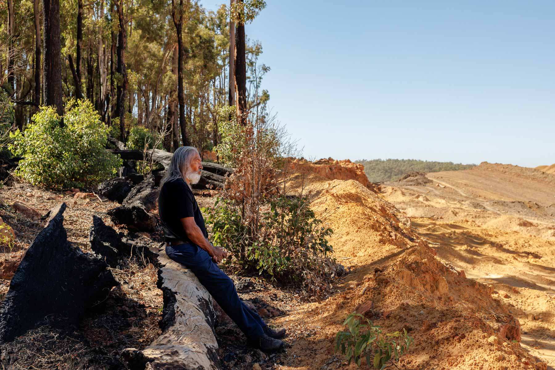 A man sits looking out over a mine.