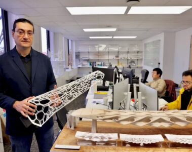 A man stands holding a long structure in a lab.